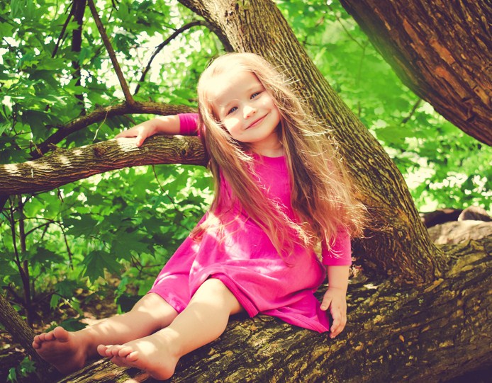 A little girl is sitting on the branch