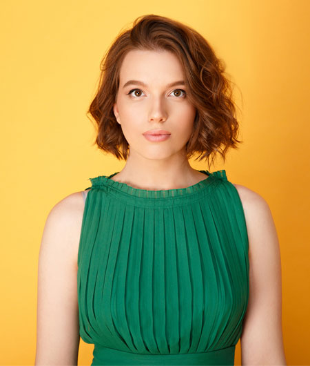 woman in green dress with short brown hair