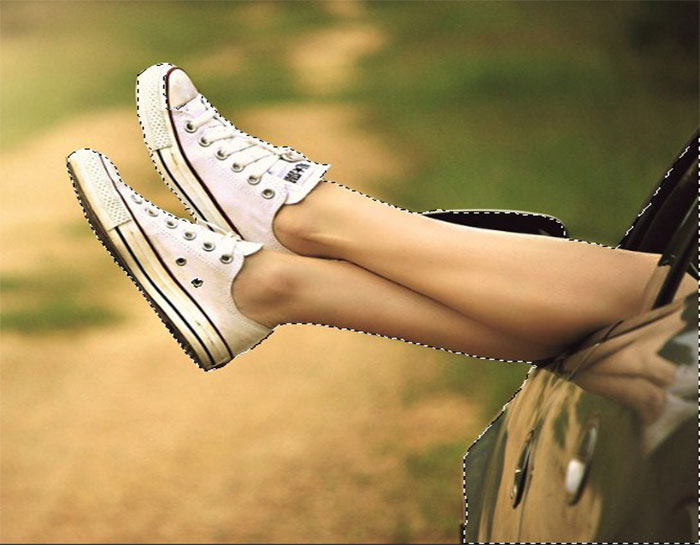 A pair of leg is outstretched out of the window of a car